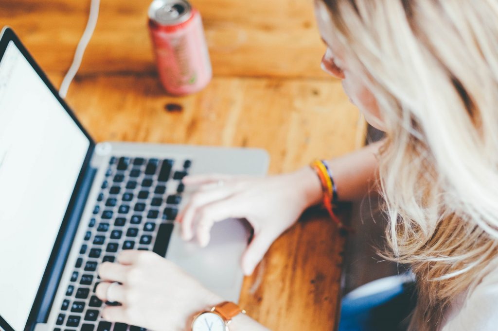 female typing on mac keyboard on wood table