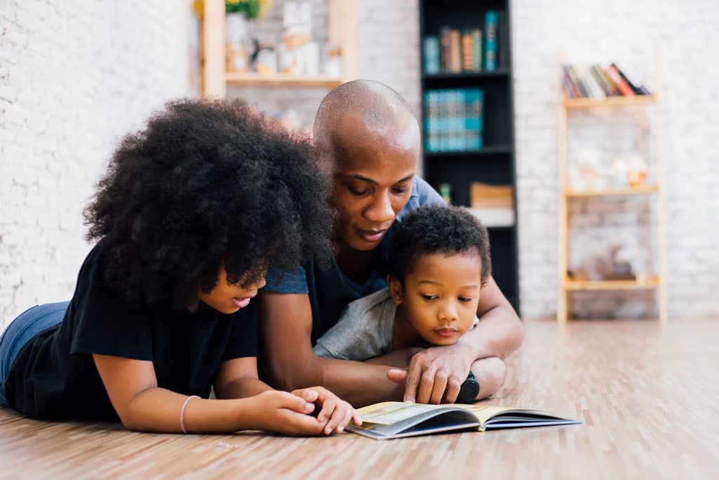 Homeschooling in Nova Scotia three people laying on the floor reading together